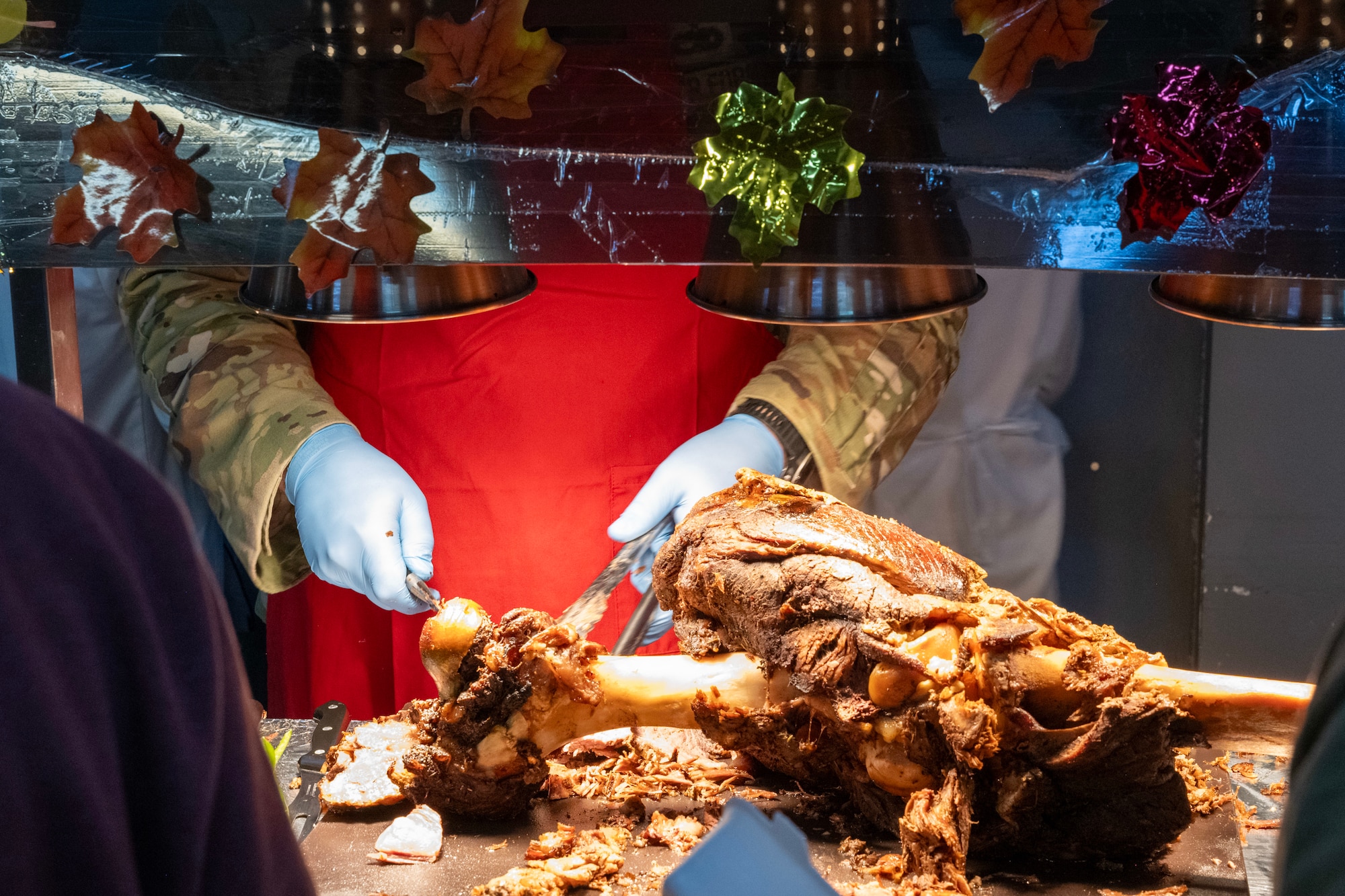 A commander works at a carving station during a Thanksgiving meal.