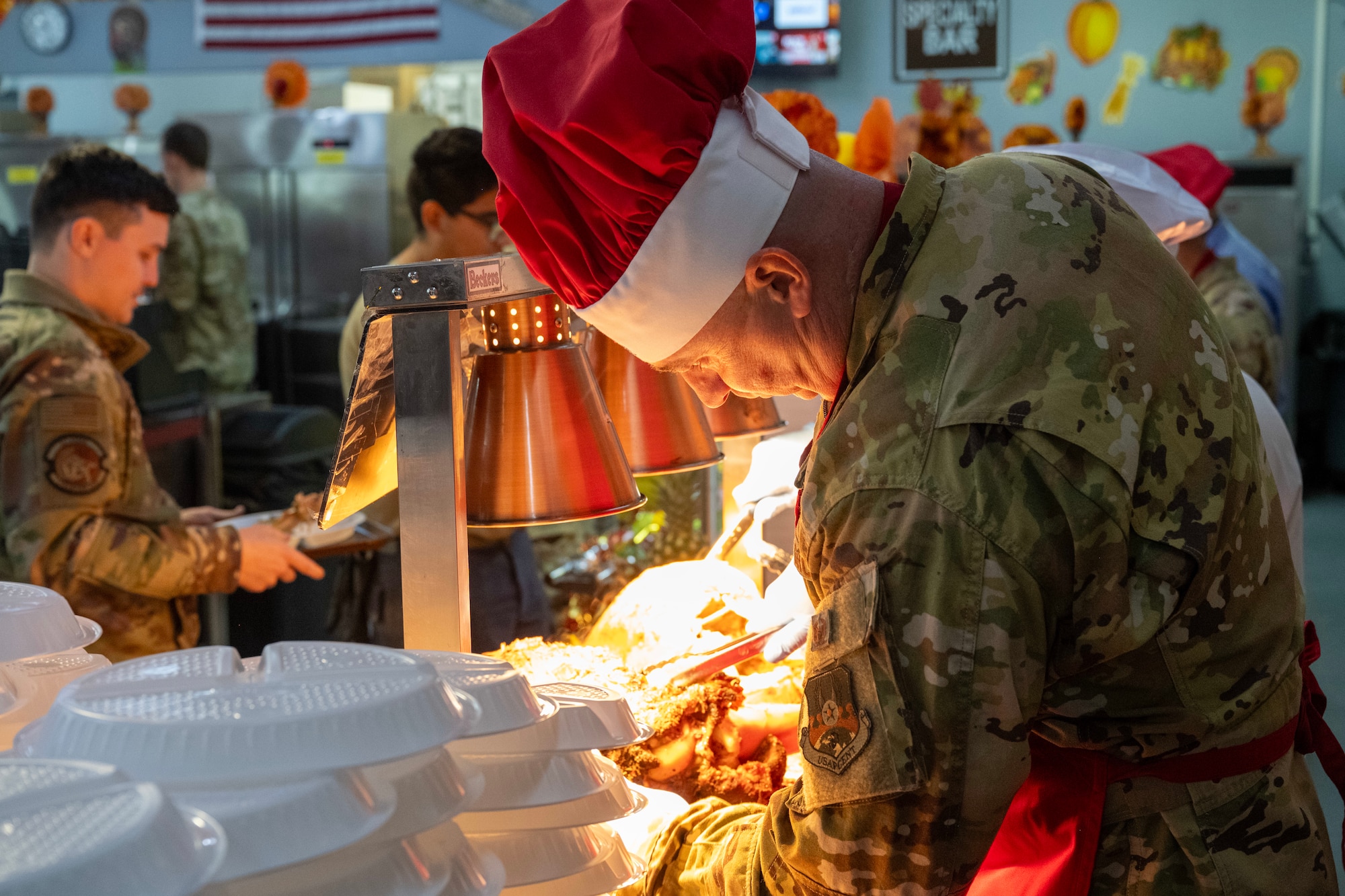 A commander works at a carving station during a Thanksgiving meal.