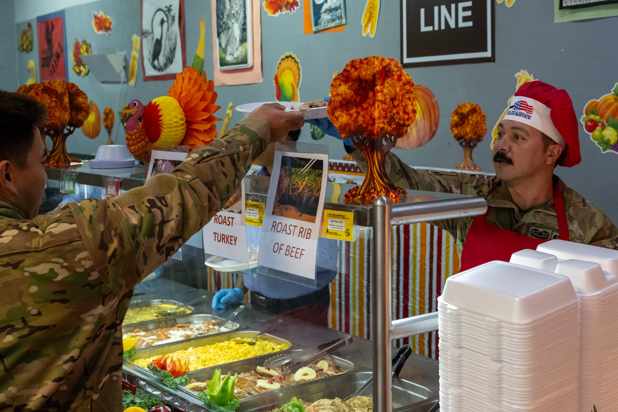 A chief master sergeant serves a plate to an Airman during a Thanksgiving meal.