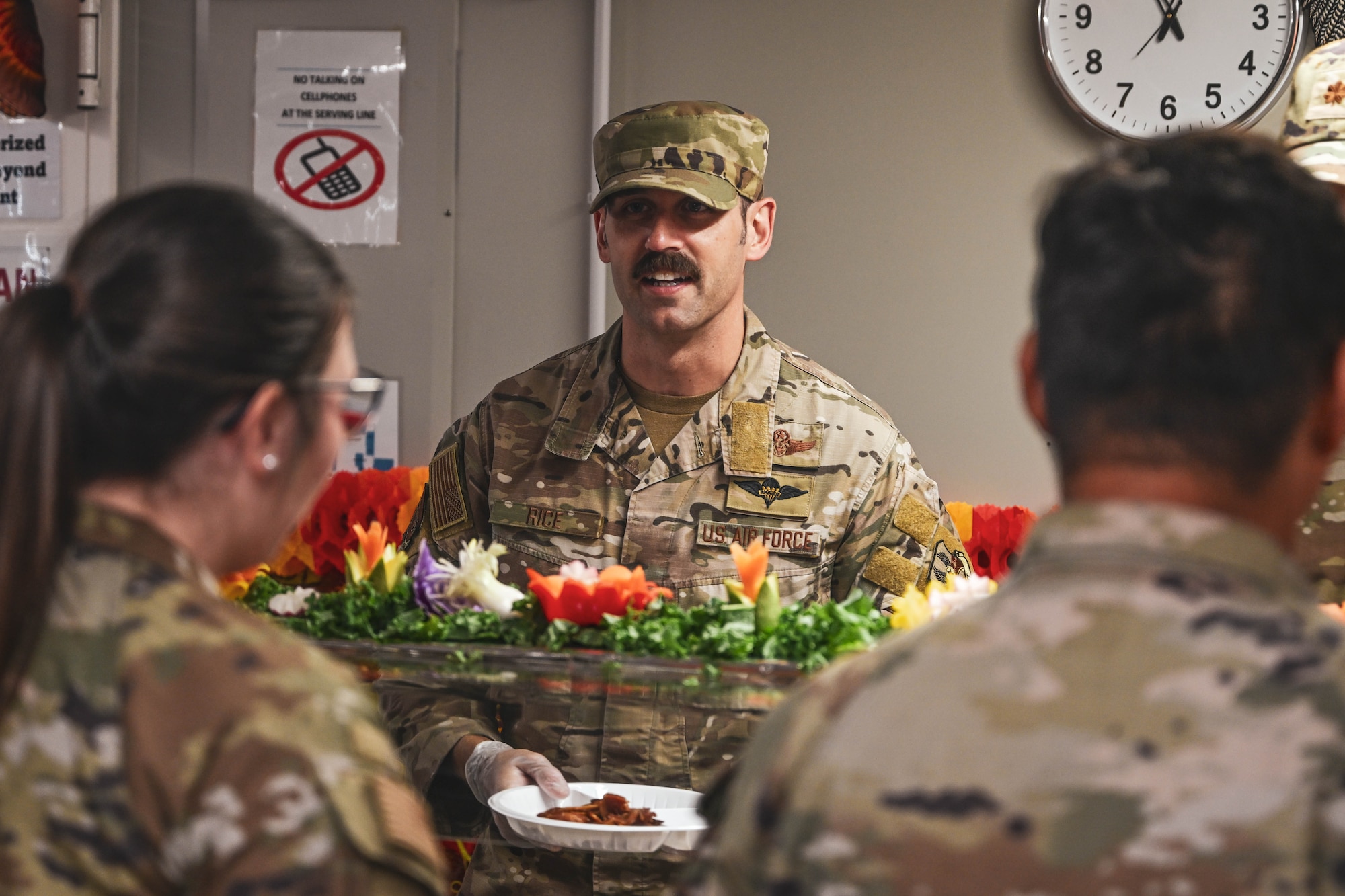A chief master sergeant serves a plate of food during a Thanksgiving meal.