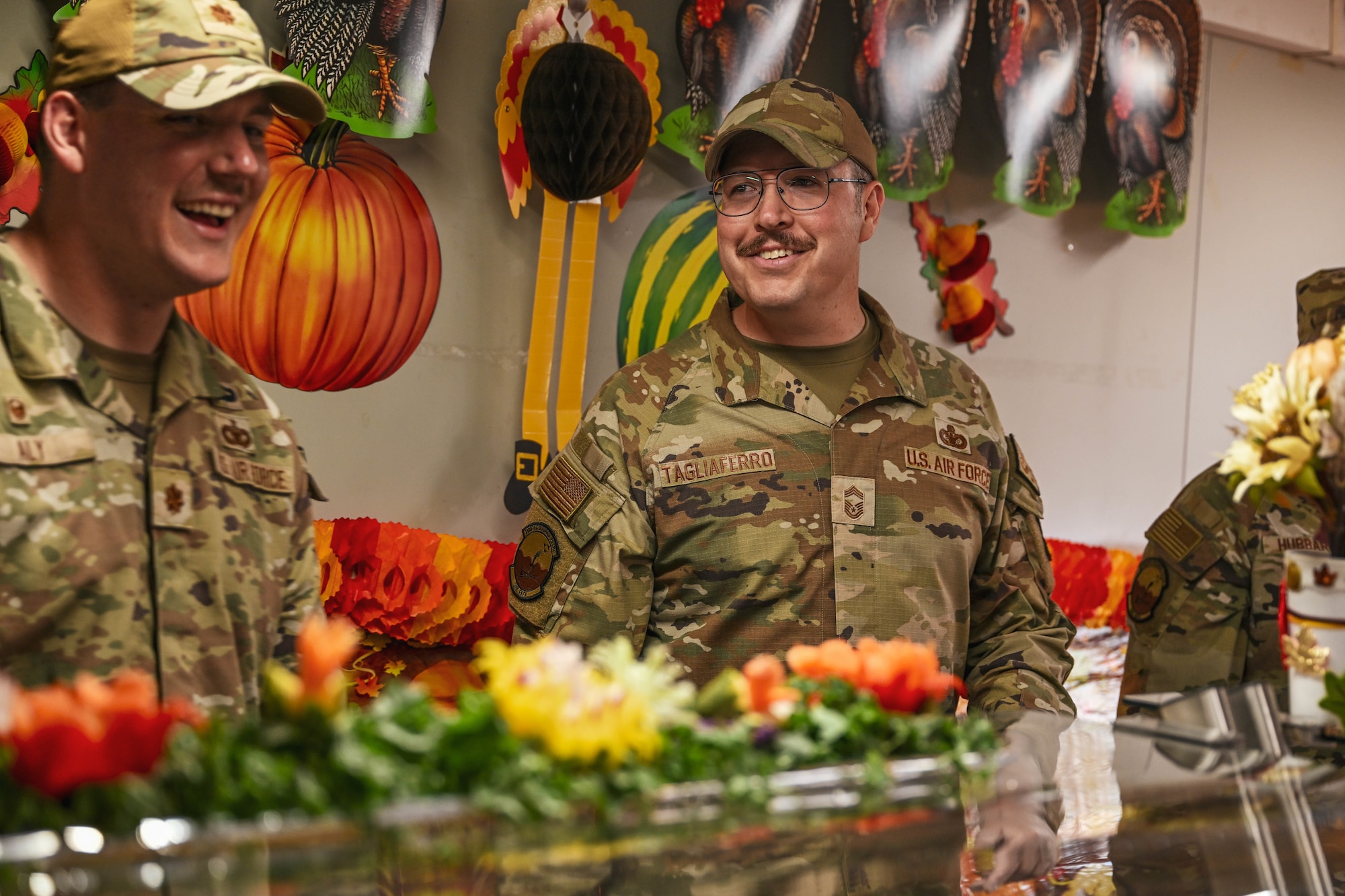 A commander and his chief serve a Thanksgiving meal at a dining facility.