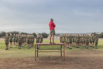 U.S. Marine Corps Chief Drill Instructor Gunnery Sgt. Crescenciano Reyes, center, with Bravo Company, 1st Recruit Training Battalion, guides recruits through dynamic warm-ups prior to a physical training event at Marine Corps Recruit Depot San Diego, California, Nov. 27, 2024. The recruits conducted a series of stations such as side shuffles, ammunition can lifts, planks, single-leg Romanian deadlifts, bicycle crunches, and 440-yard sprints during their physical training event, strengthening themselves physically and mentally. (U.S. Marine Corps photo by Cpl. Alexandra M. Earl)