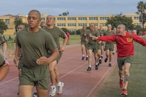 U.S. Marine Corps Drill Instructor Staff Sgt.Tristian Shank, right, with Bravo Company, 1st Recruit Training Battalion, guides recruits through a 440-yard sprint during a physical training event at Marine Corps Recruit Depot San Diego, California, Nov. 27, 2024. The recruits conducted a series of stations such as side shuffles, ammunition can lifts, planks, single-leg Romanian deadlifts, bicycle crunches, and 440-yard sprints during their physical training event, strengthening themselves physically and mentally.  (U.S. Marine Corps photo by Cpl. Alexandra M. Earl)