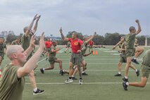 U.S. Marine Corps Drill Instructor Sgt. Bronson Sahut, center, with Bravo Company, 1st Recruit Training Battalion, observes recruits executing exercise during a physical training event at Marine Corps Recruit Depot San Diego, California, Nov. 27, 2024. The recruits conducted a series of stations such as side shuffles, ammunition can lifts, planks, single-leg Romanian deadlifts, bicycle crunches, and 440-yard sprints during their physical training event, strengthening themselves physically and mentally. (U.S. Marine Corps photo by Cpl. Alexandra M. Earl)