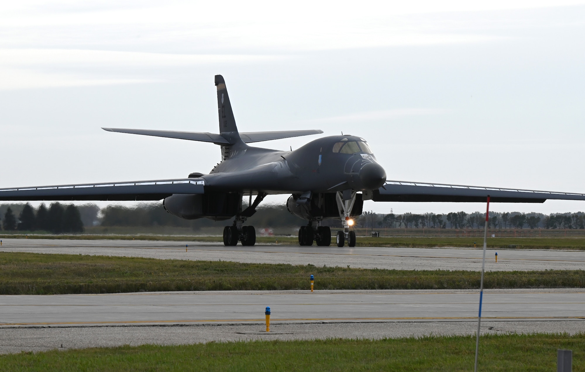 B-1B Lancer taxis on grey runway.