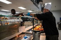 U.S. Air Force Brig. Gen. Lawrence Sullivan, right, the 57th Wing commander, serves a Thanksgiving meal to Airman 1st Class Eugene Sasu Barfour, a 99th Civil Engineer Squadron Pest Management apprentice, at the Crosswinds Dining Facility, Nellis Air Force Base, Nevada, Nov. 28, 2024.