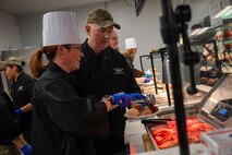 U.S. Air Force Col. Jason Wild, right, the 99th Air Base Wing deputy commander and his wife Drea Wilde serve a Thanksgiving meal at the Crosswinds Dining Facility, Nellis Air Force Base, Nevada, Nov. 28, 2024.