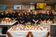 Leadership and Airmen assigned to Nellis Air Force Base, Nevada, pose for a group photo after serving Thanksgiving meals at the Crosswind Dining Facility, Nov. 28, 2024.
