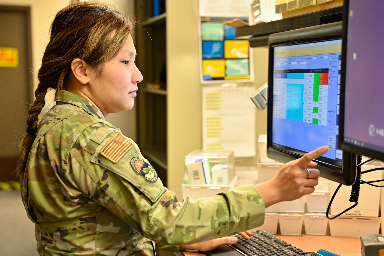 An airman works on a computer and touches the screen.