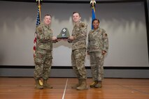 An Airman receives an award from U.S. Air Force Col. Jason Glynn.