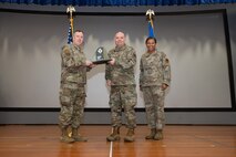 An Airman receives an award from U.S. Air Force Col. Jason Glynn.