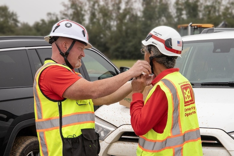 Hurricane Helene debris removal safety office Gary Little from Mobile District, adjusts the new safety helmet on a quality assurance specialist. Little says the helmets with the chin strap provides additional protection from head injuries.