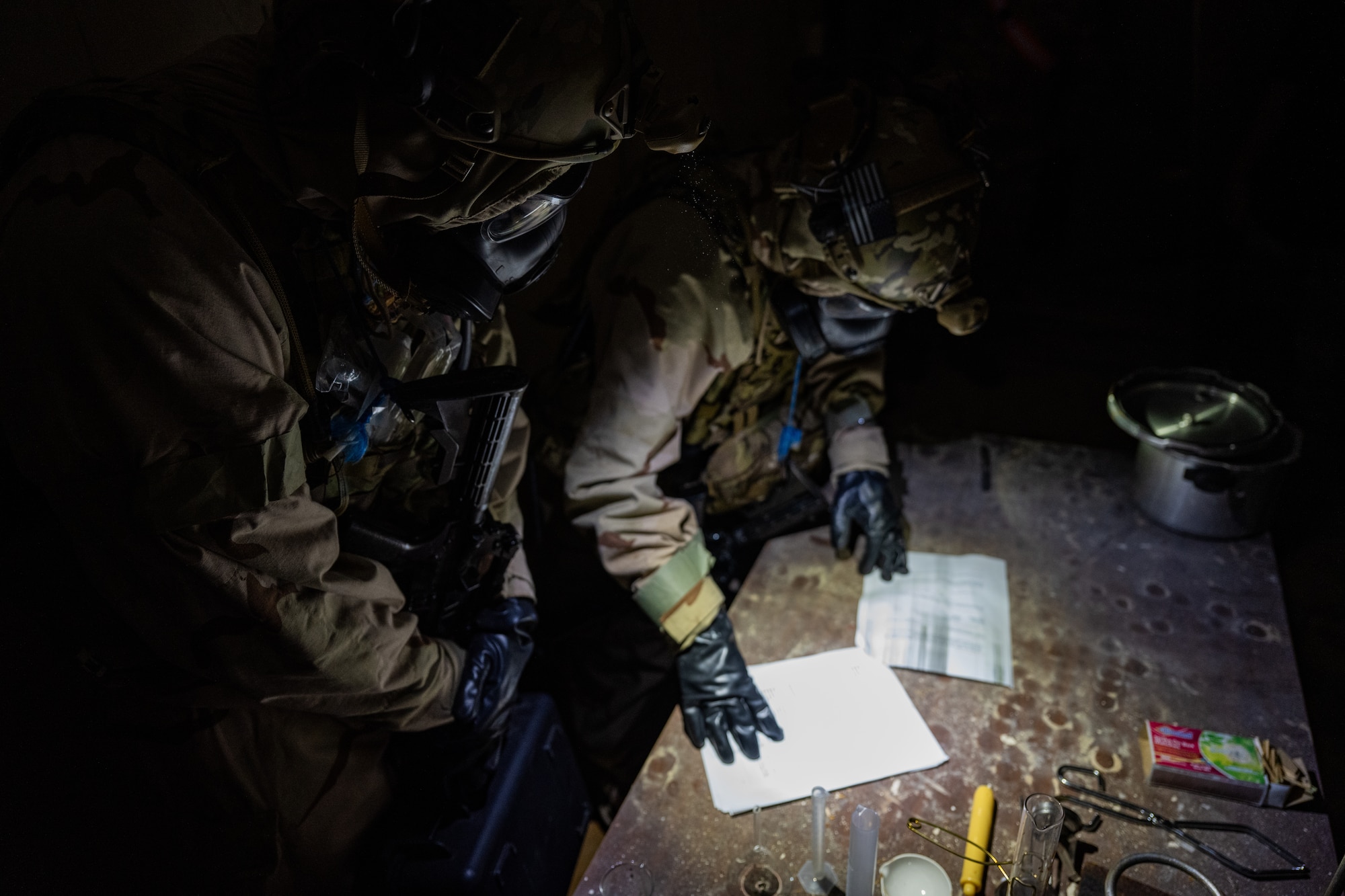 U.S. Airmen, assigned to the 1st Special Operations Civil Engineer Squadron explosive ordnance disposal team, read a document found in a World War II era bunker’s chemicals lab during a bivouac exercise at Eglin Range, Eglin Air Force Base, Florida, Nov. 6, 2024. Throughout the exercise participants practiced weapons handling, self-aid buddy care, dismounted patrol missions and operational security while demonstrating their ability to survive and operate in a hostile environment. (U.S. Air Force photo by Senior Airman Hussein Enaya)