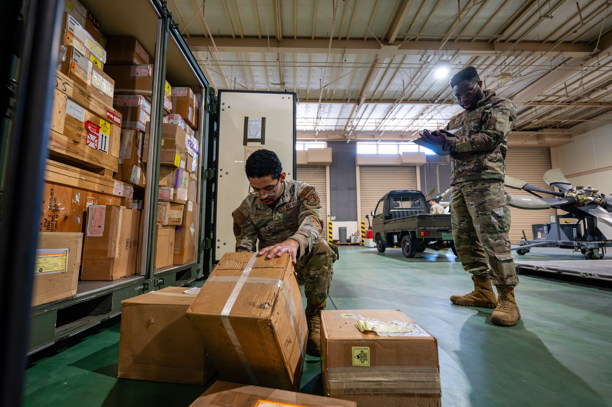 U.S. Air Force Tech. Sgt. Semevo Hounkpatin, 374th Logistics Readiness Squadron inventory and inspection section chief, and Senior Airman Djavion Poppell, 374th LRS aircraft parts store journeyman, conduct an inventory of aircraft maintenance items for Operation Christmas Drop 2024 at Yokota Air Base, Japan.