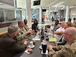 A group of people sitting around a table are having a disucssion.