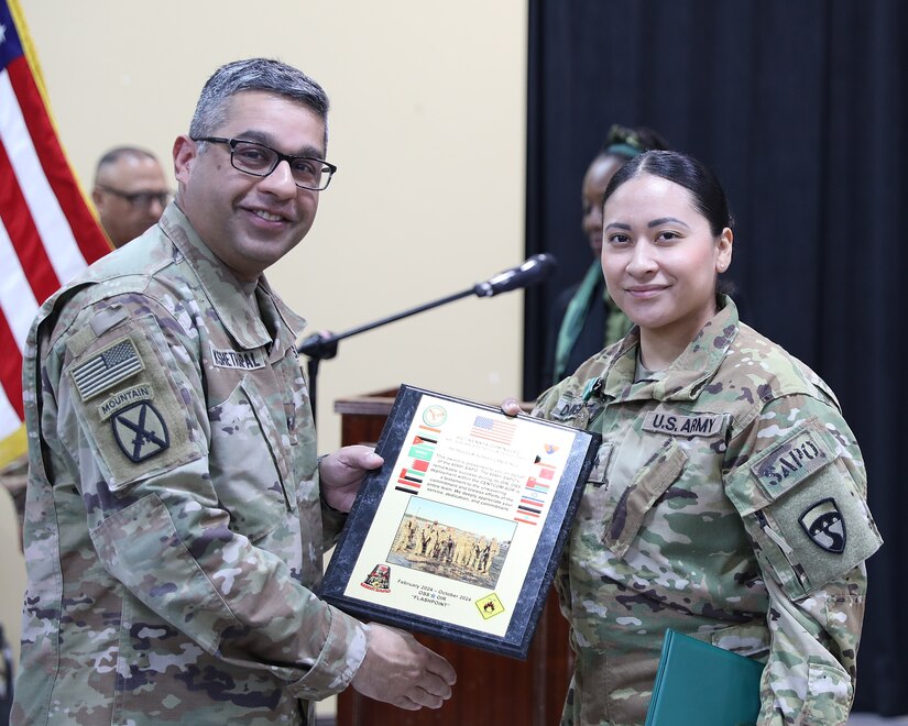 A leader presents a plaque to a Soldier.