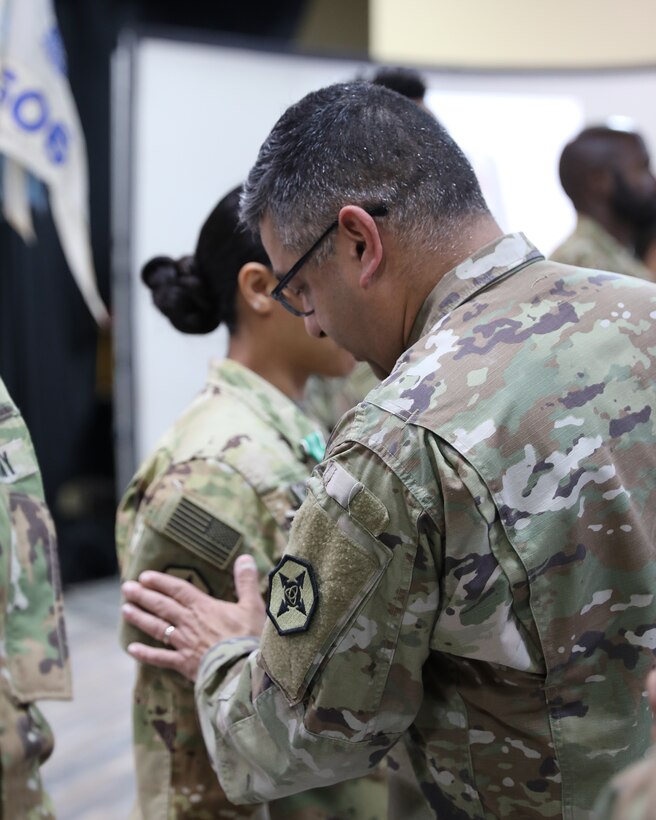 A leader places a unit patch on a Soldier’s right sleeve.