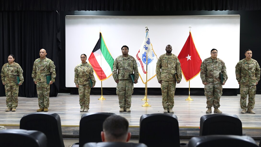 Soldiers from the 606th Quartermaster Detachment stand on stage