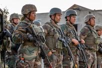 Lt. Constancia Nzang Abaga of Equitorial Guinea's National Gendarmarie and students from the Inter-American Air Force's Academy's Ground Defense Leadership Course hold training weapons after conducting a capstone exercise, Oct. 11, 2024 at Joint Base San Antonio-Camp Bullis, Texas.