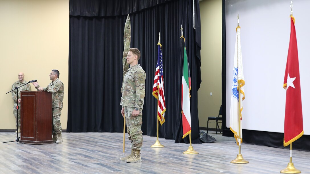 Soldier stands at attention with unit's cased guidon.