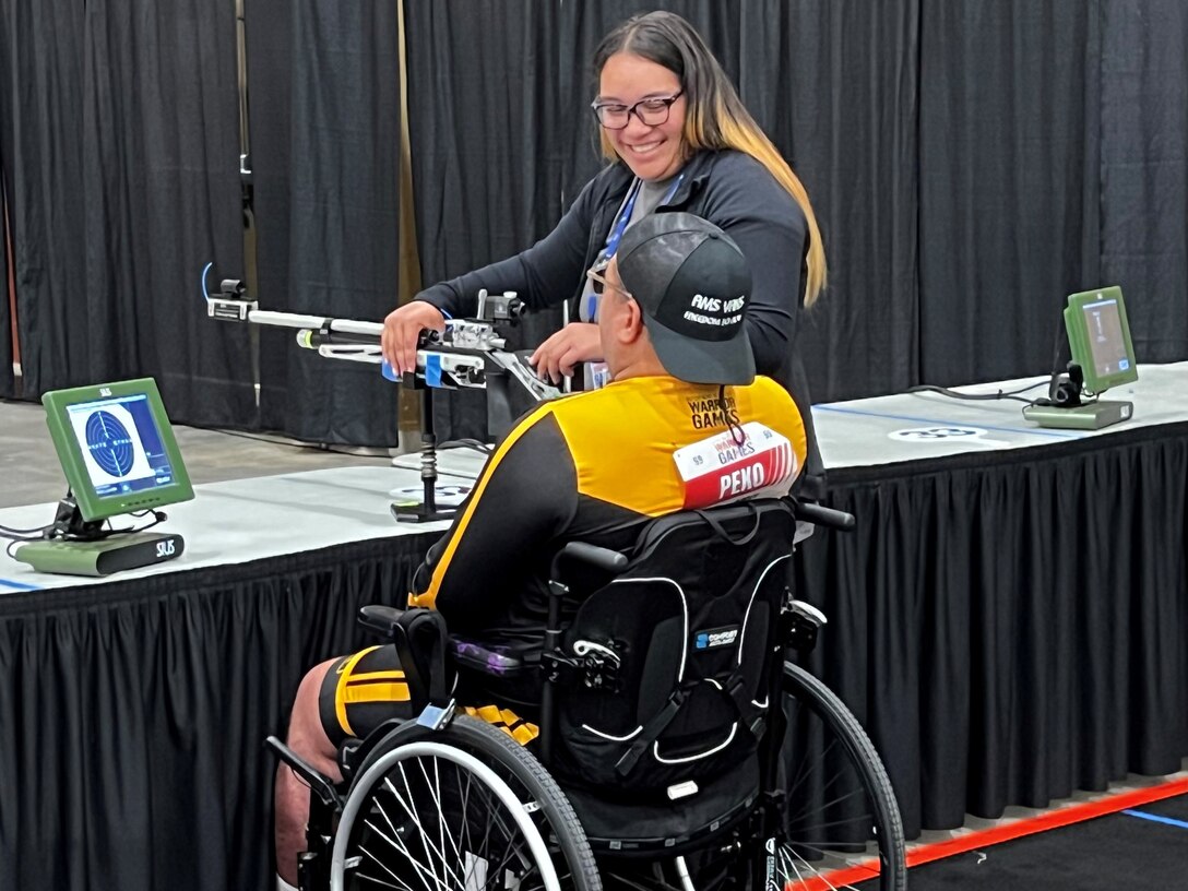 Gloriah Peko assists her husband, Sgt. 1st  Jack Peko, in a shooting competition at the 2024 DOD Warrior Games