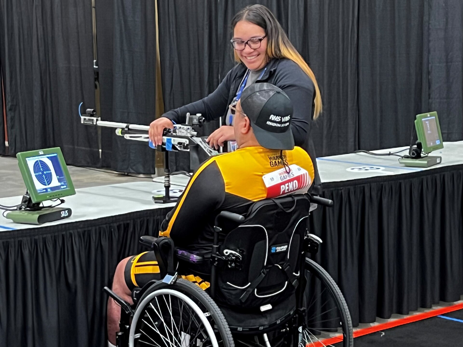Gloriah Peko assists her husband, Sgt. 1st  Jack Peko, in a shooting competition at the 2024 DOD Warrior Games