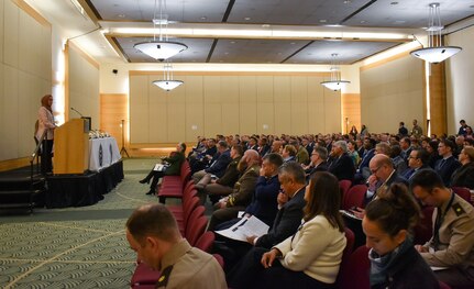 Security Cooperation personnel sit in a conference room listening to a guest speaker