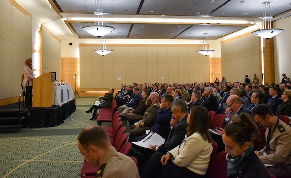Security Cooperation personnel sit in a conference room listening to a guest speaker