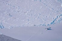 Submarine appearing through ice, parachuters landing on ice field