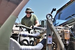Marine looks over engine of vehicle