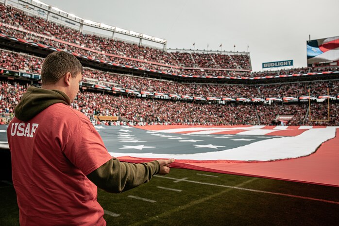 A U.S. Airman holds the American Flag during the National Anthem before the San Francisco 49ers Salute to Service game vs. the Seattle Seahawks at Levi’s Stadium Santa Clara, California. Nov. 17, 2024. U.S. service members participated in the Salute to Service game to help honor the nation's service members, veterans and their families. (U.S. Marine Corps photo by Cpl. Sarah M. Grawcock)