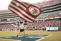 A participant of the San Francisco 49ers Salute to Service game vs. the Seattle Seahawks waves a flag at Levi’s Stadium Santa Clara, California. Nov. 17, 2024. U.S. service members participated in the Salute to Service game to help honor the nation's service members, veterans and their families. (U.S. Marine Corps photo by Cpl. Sarah M. Grawcock)