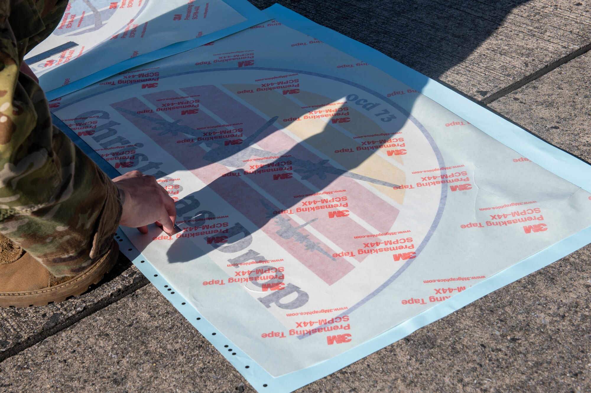 An Airman prepares a colorful logo by using a measuring stick to measure it's dimensions.
