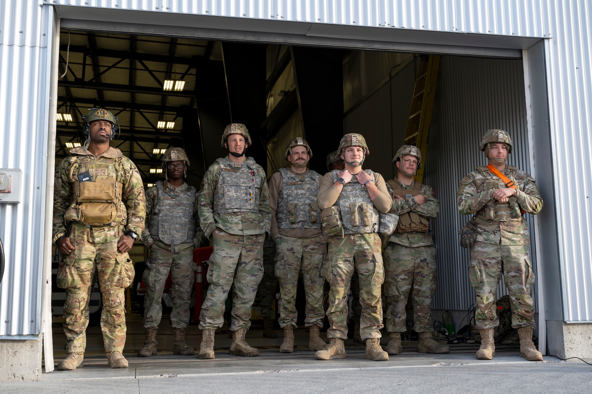 A group of people stand by a hangar entrance