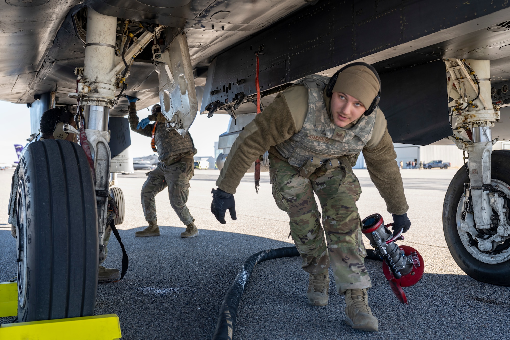 A man drags a fuel hose out from under a jet