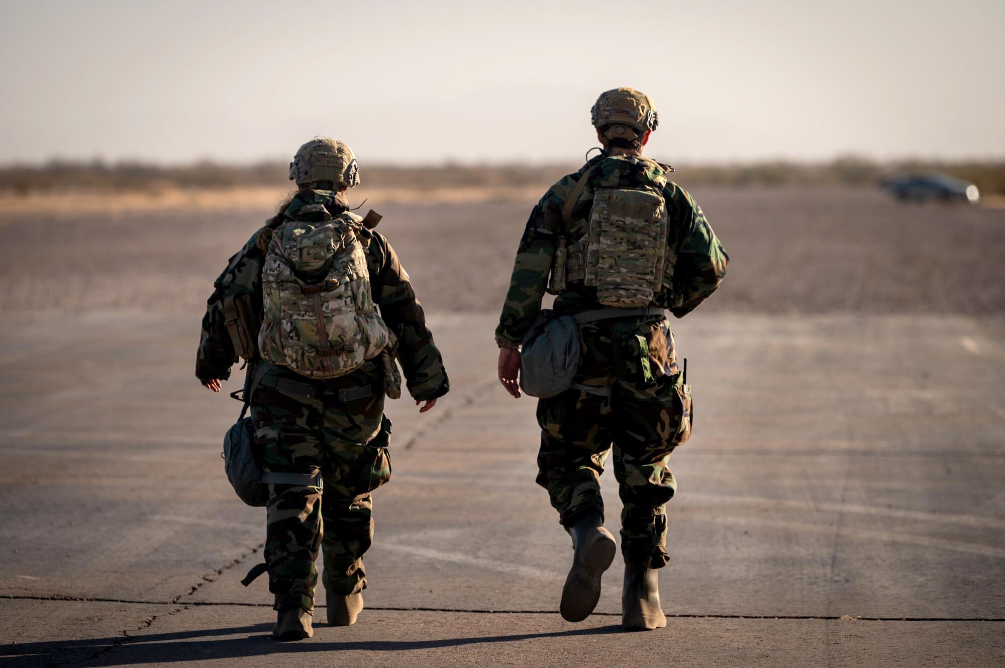 Two 944th Fighter Wing U.S. Air Force Reserve Citizen Airmen dawn their Mission Oriented Protective Posture (MOPP) gear and walk together after completing a patrol during Exercise Desert Hammer 25-1 at Auxiliary Field 6 near Gila Bend, Ariz., Nov. 15, 2024. This large-scale exercise showcases the adaptability of Mission Ready Airmen, advancing the skills needed to thrive in the rapidly evolving challenges of global competition. (U.S. Air Force photo by Senior Airman Jacob Dastas)
