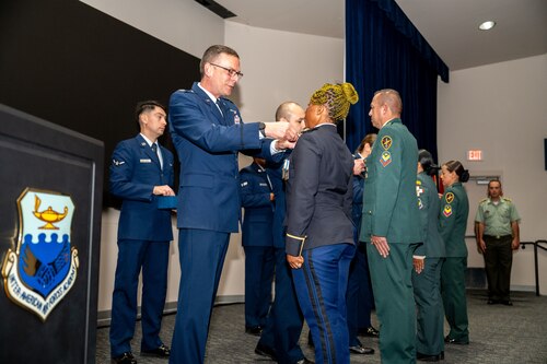 Col. Bryan Tuinman, Commandant of the Inter-American Air Forces Academy, pins Lt. Constancia Nzang Abaga of Equitorial Guinea’s National Gendarmarie during a graduation ceremony at Joint Base San Antonio-Lackland, Texas, Oct. 17, 2024.