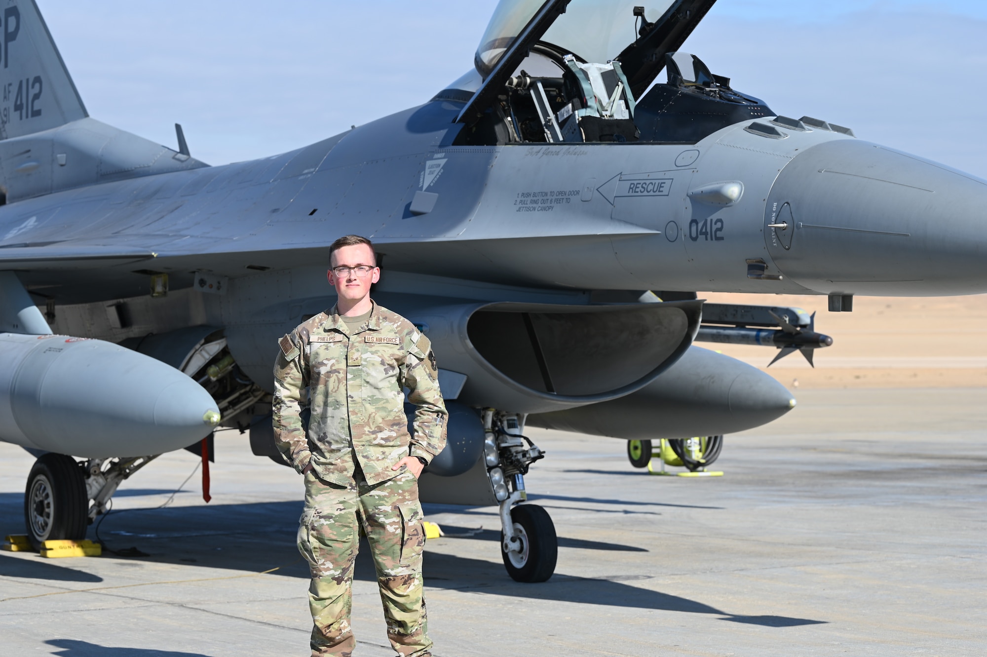 U.S. Air Force Senior Airman Roland Phelps, 378th Air Expeditionary Wing Host Nation Coordination Cell cryptologic language analyst, stands in front of an F-16 Fighting Falcon in a U.S. Central Command area of responsibility, Nov. 28, 2024.