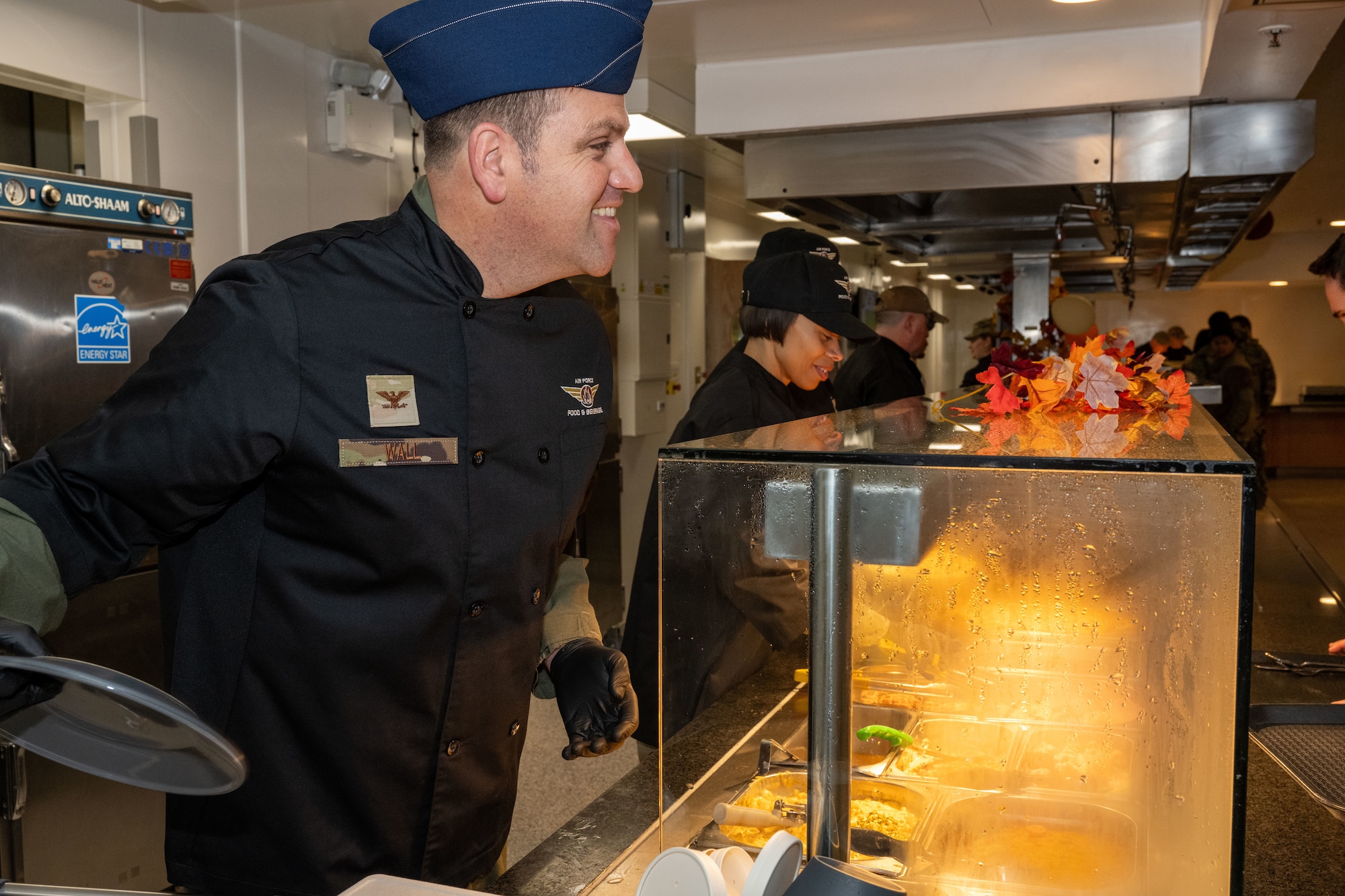 U.S. Air Force Col. Joseph Wall, left, 100th Air Refueling Wing deputy commander, and Chief Master Sgt. Tiffany Griego, 100th ARW command chief, serve Thanksgiving food at Royal Air Force Mildenhall, England, Nov. 27, 2024.