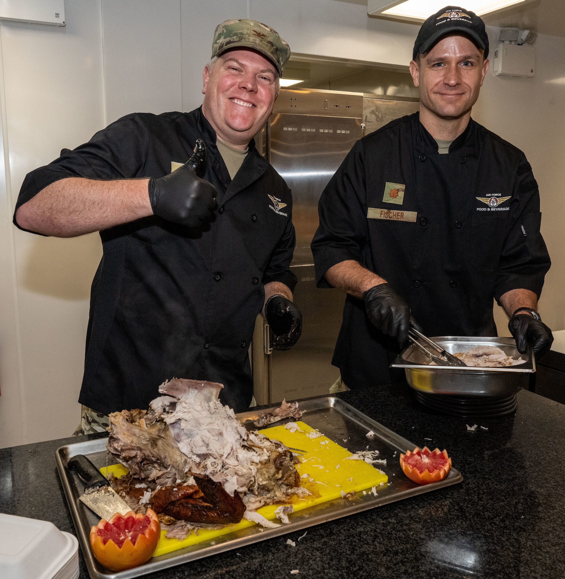 U.S. Air Force Col. Adam Moore, left, 352nd Special Operations Wing commander, and Maj. Lee Fischer, 321st Special Tactics Squadron commander, serve turkey at Royal Air Force Mildenhall, England, Nov. 27, 2024.