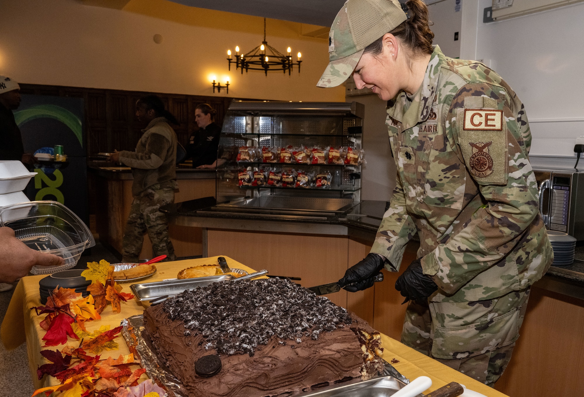 U.S. Air Force Lt. Col. Anna Narduzzi, 100th Civil Engineer Squadron commander, slices and distributes dessert at Royal Air Force Mildenhall, England, Nov. 27, 2024.
