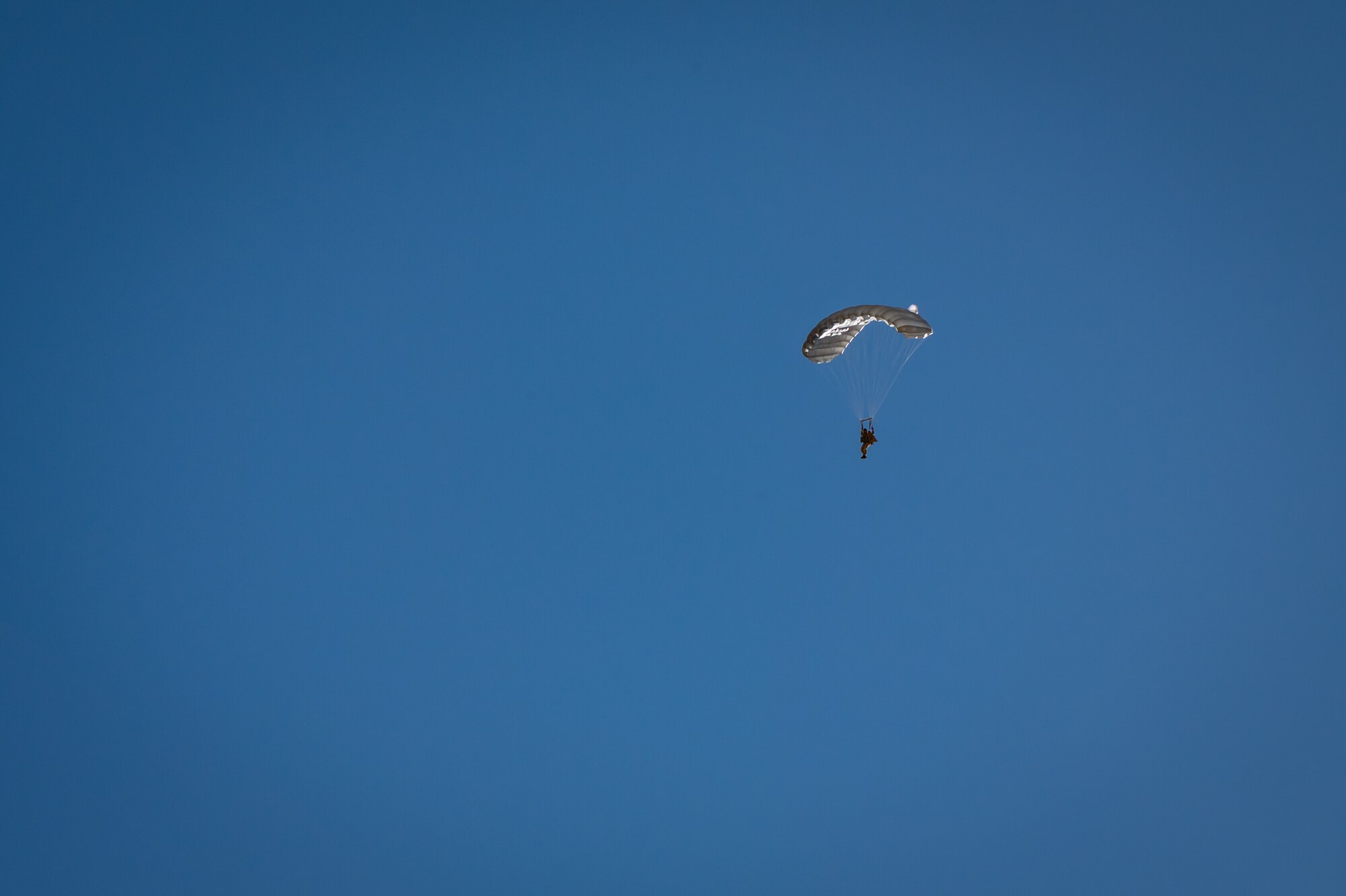 A U.S. Air Force Airman descends under canopy during a personnel airdrop at Exercise Desert Hammer 25-1, held at Auxiliary Airfield 6 near Gila Bend, Ariz., Nov. 14, 2024. Through joint and multinational collaboration, Desert Hammer tests the ability of over 700 participants and 131 aircraft to operate, defend, and sustain airbases under austere conditions. (U.S. Air Force photo by Tech. Sgt. Tyler J. Bolken)