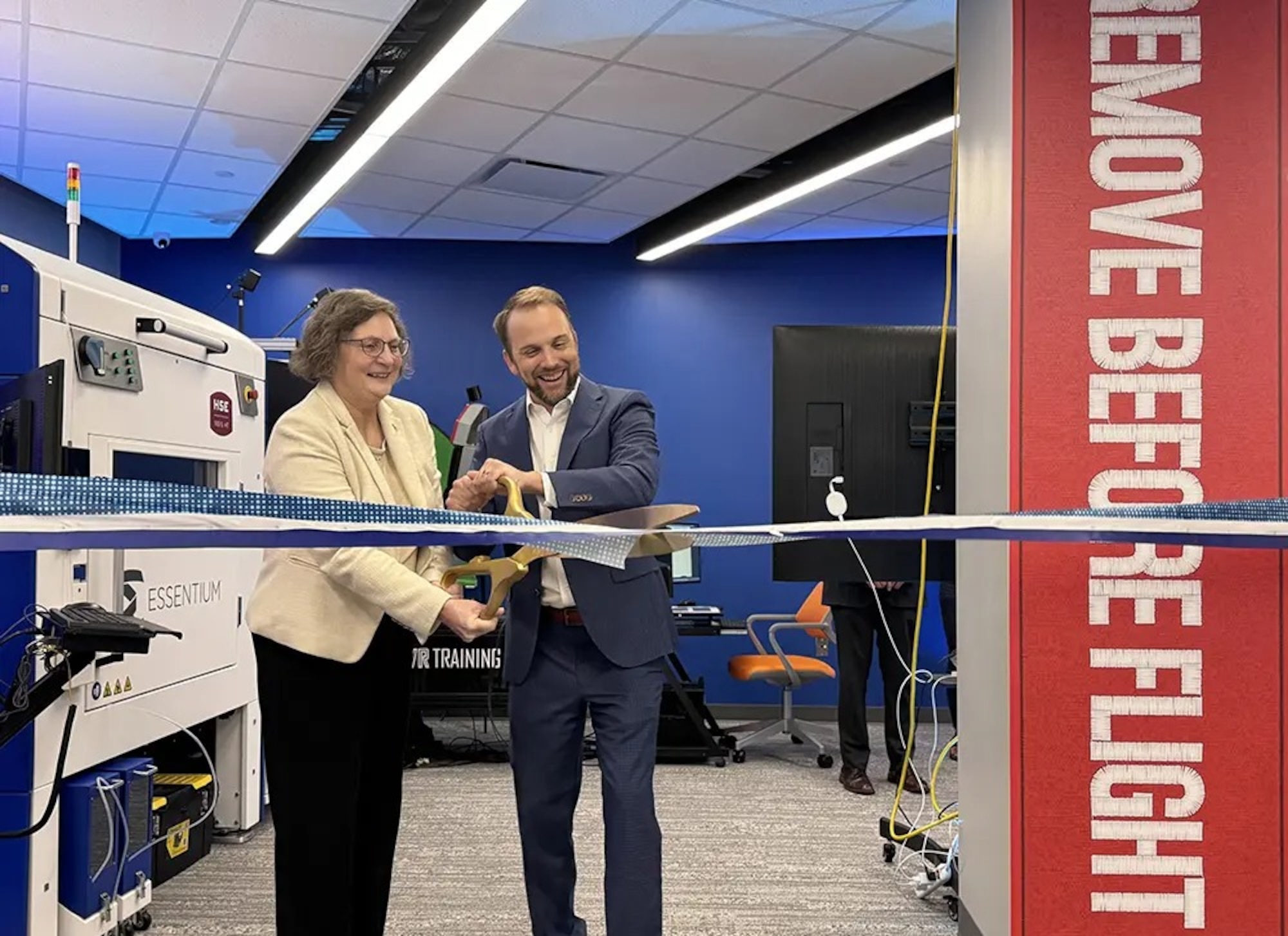 Two people stand and cut a large ribbon together during a new facility's opening ceremony