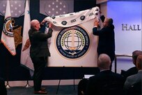 DSCA Director Mike Miller and DSCS Director Saul Bracero unveil the DSCS logo at the opening ceremony of DSCS