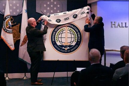 DSCA Director Mike Miller and DSCS Director Saul Bracero unveil the DSCS logo at the opening ceremony of DSCS