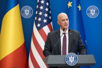 Director of DSCA Mr. Michael Miller stands at a podium with Romanian and American flags behind him as he discussed the $920 million FMF direct loan to our partner and ally, Romania.