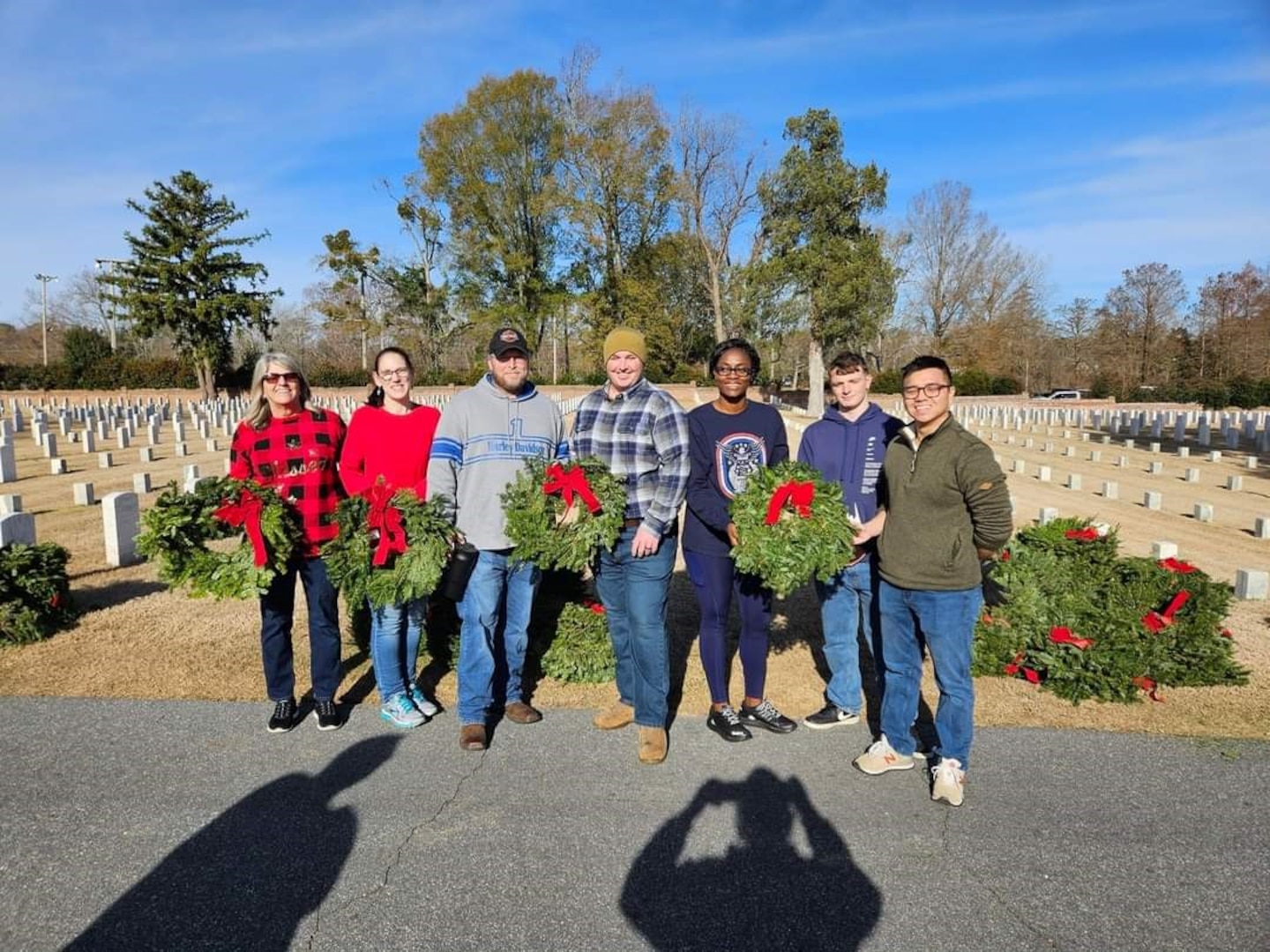 Mrs. Amanda Pick and her husband John, second and third from left, and fellow staff members of Naval Health Clinic Cherry Point at the Wreaths Across America wreath laying event December 16, 2023 at the New Bern, North Carolina National Cemetery.  The Picks share a passion to honor America’s deceased service members every holiday season through their volunteer work with Wreaths Across America.  Both serve aboard Naval Health Clinic Cherry Point, John as a General Schedule Financial Technician and Amanda as a contracted Supply Technician.  (Contributed Photo)