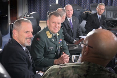 Six men sit at a table talking.