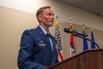 LtC Hassell, 57th Fighter Squadron commander, speaks from behind a podium during a ceremony for the reactivation of the 85th Fighter Group and 57th Fighter Squadron.