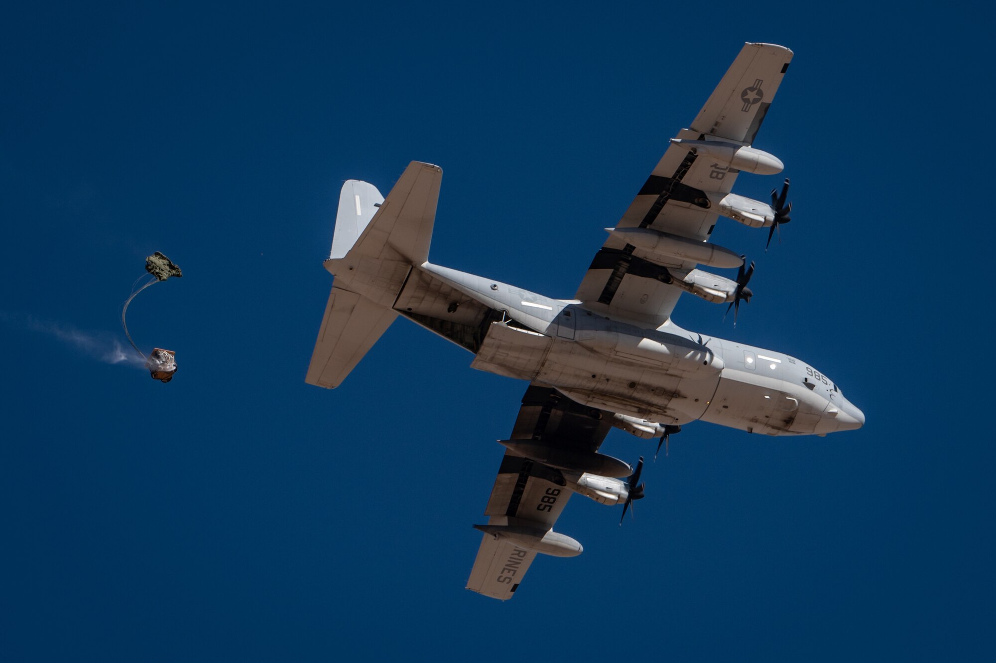 Cargo descends under a parachute from a U.S. Marine Corps KC-130J Hercules during Exercise Desert Hammer 25-1 at Auxiliary Airfield 6 near Gila Bend, Ariz., Nov. 14, 2024. The exercise integrates Agile Combat Support and Large Force Exercise capabilities in a contested environment. (U.S. Air Force photo by Tech. Sgt. Tyler J. Bolken)